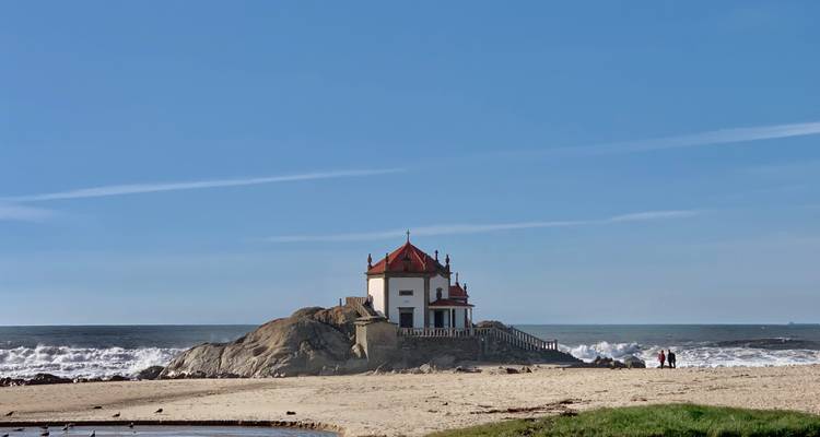 Kapel op een rotsachtige uitstulping bij de zee, met golven die nabij beuken.