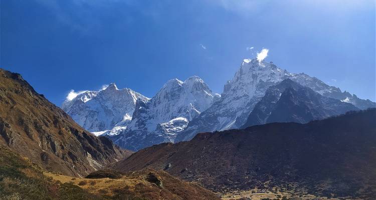 Un paysage montagneux pittoresque avec des sommets enneigés sous un ciel bleu dégagé.