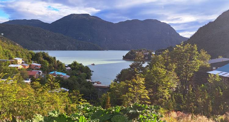Seeblick mit Hügeln, Häusern und Bäumen.