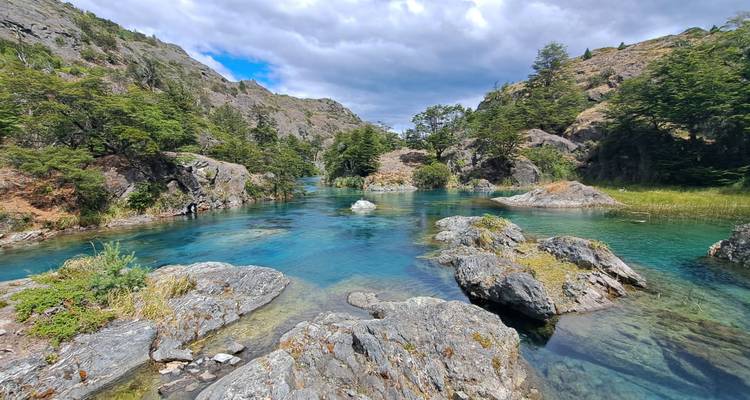 Klarer blauer Fluss, der durch eine felsige Landschaft fließt.