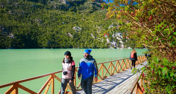 Touristen, die auf einem Holzweg in der Nähe eines Sees spazieren gehen.