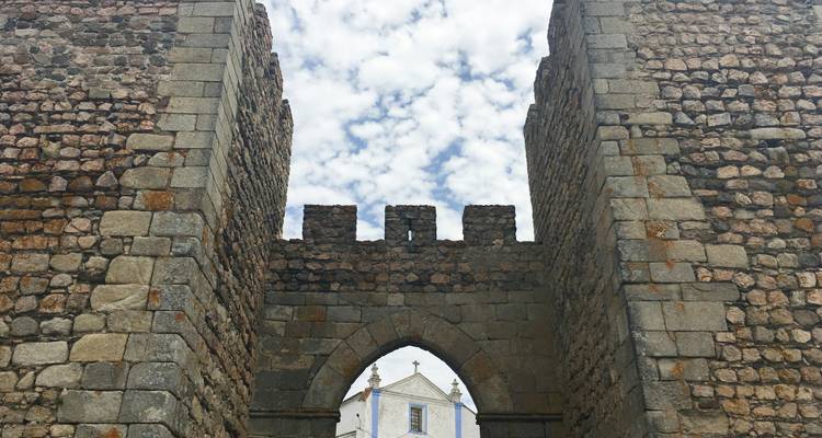Arche de pierre ancienne avec un ciel lumineux derrière.