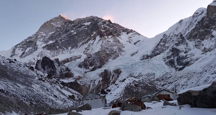Een bergachtig landschap bedekt met sneeuw en kleurrijke gebedsvlaggen.