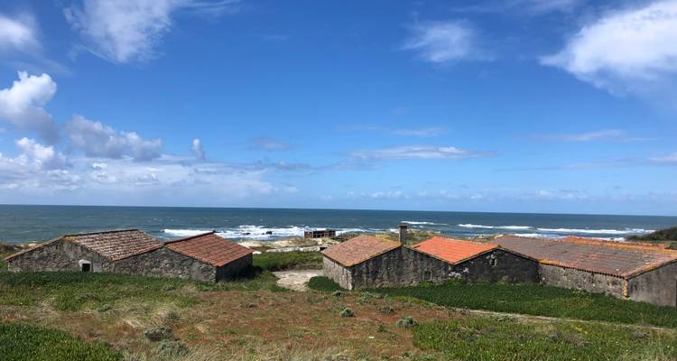Paysage côtier accidenté avec de vieux bâtiments en pierre et l'océan.