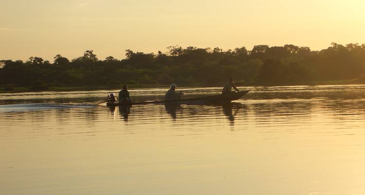 Mensen in een kano op een rivier bij zonsondergang.