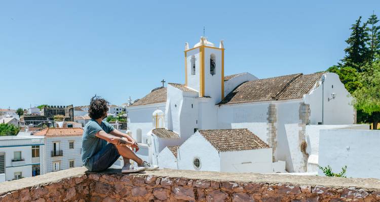 Personne assise sur un rebord surplombant une ville blanche avec une église.