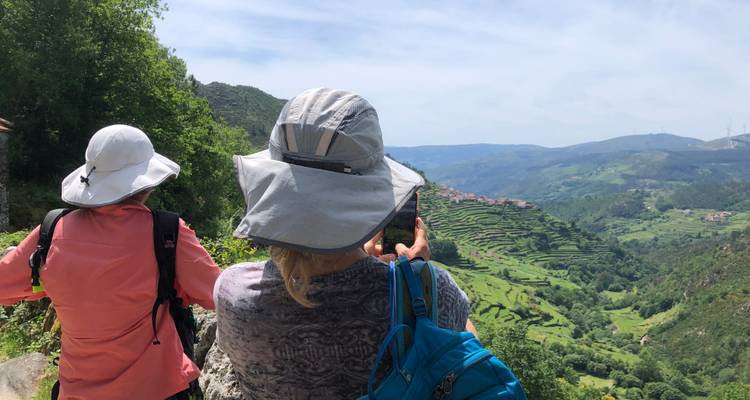 Two people taking photos of terraced hills.