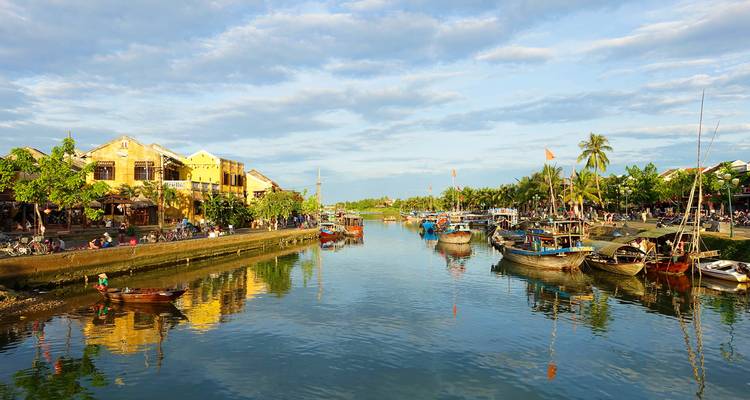 Scenic river with boats and historical buildings.