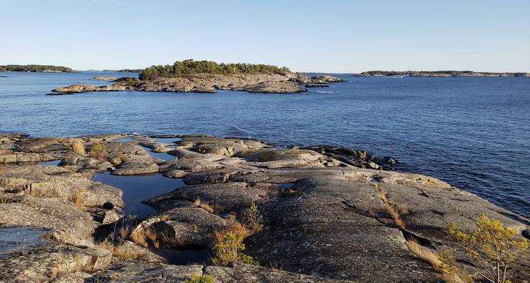 Rocky coastline with small islets under a blue sky.