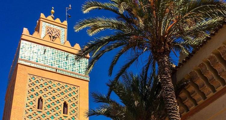 A vibrant view of a tall tiled minaret beside a palm tree.