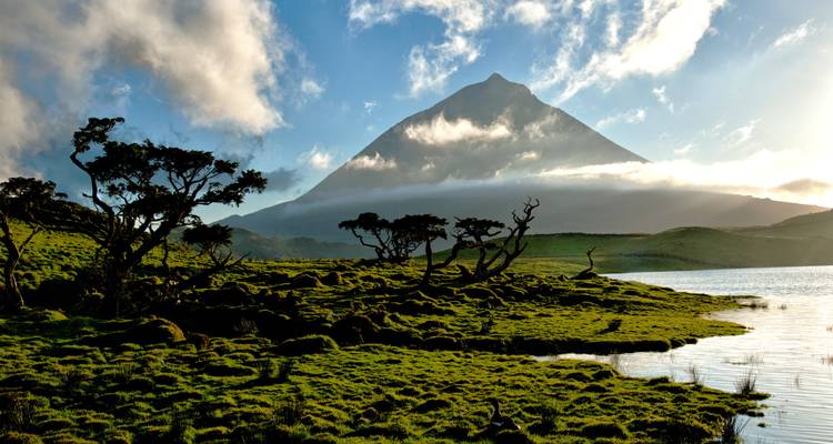 Vista panorámica del monte Pico con nubes dramáticas y reflejo en el lago.