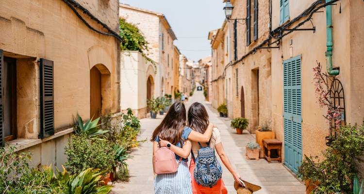 Back view of two women walking down a picturesque street.