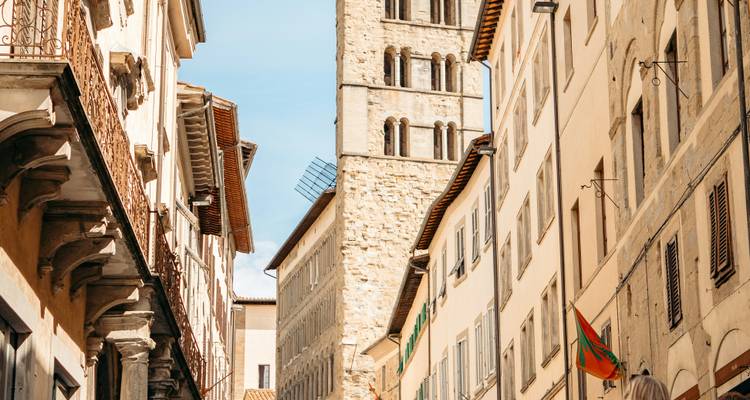 Enge Straße in Florenz mit historischen Gebäuden und einem Turm im Hintergrund.