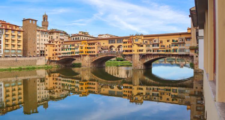 Ponte Vecchio spiegelt sich perfekt im Arno wider mit der Skyline von Florenz dahinter.