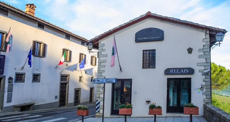 Kleine toskanische Dorfstraße mit Flaggen und Schild für Country Relais im Morgenlicht.