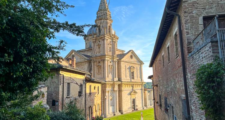 Elegante Renaissance-Kirche San Biagio, eingerahmt von rustikalen Steingebäuden bei Sonnenuntergang.