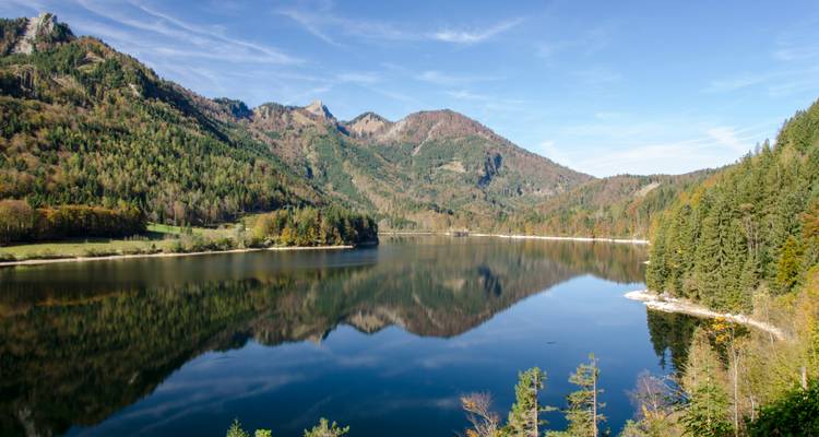 Lake surrounded by forested mountains with clear reflections.