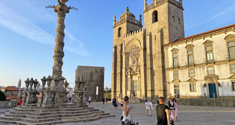 Offener Platz vor der Kathedrale von Porto mit Touristen, die die historische Steinarchitektur im warmen Licht bewundern.