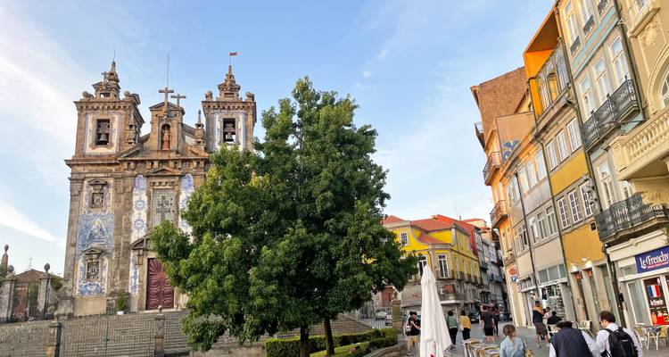 Kachelverkleidete Kirche und lebhafte Straße mit Cafés und Einkäufern im historischen Zentrum von Porto.