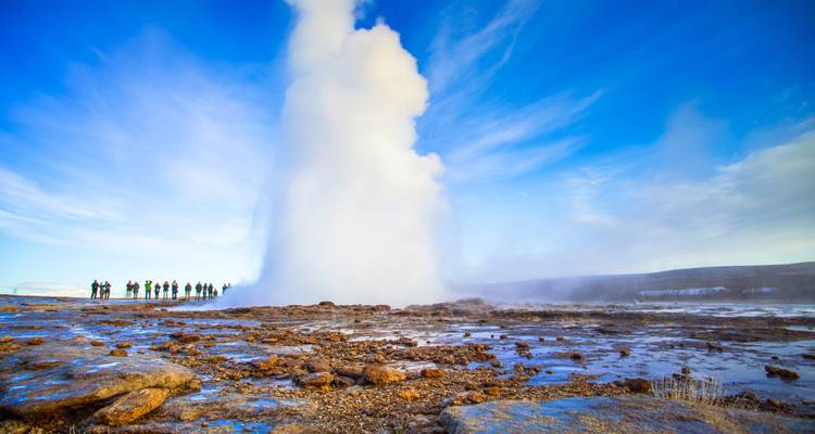 Geyser en éruption avec un groupe de personnes qui regardent.
