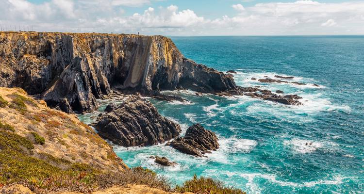 Falaises escarpées au bord de l'océan sous un ciel bleu.