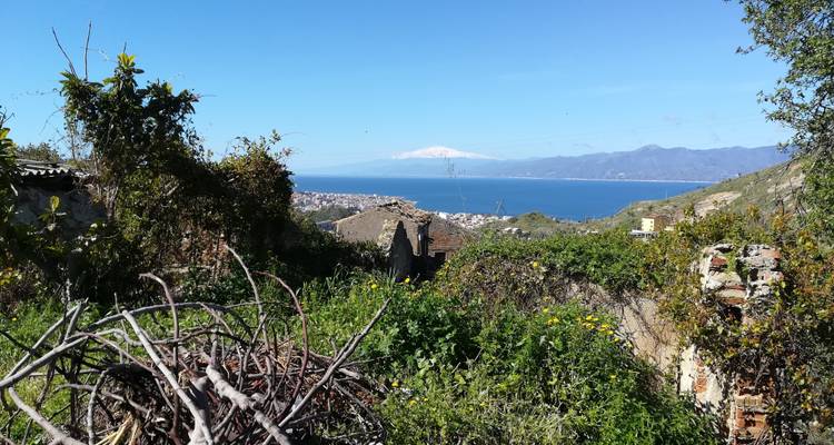 Una vista panorámica sobre un pueblo costero hacia el mar con una montaña distante.