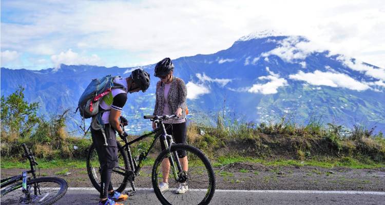 Deux cyclistes faisant une pause avec une vue imprenable sur une montagne et une vallée luxuriante.
