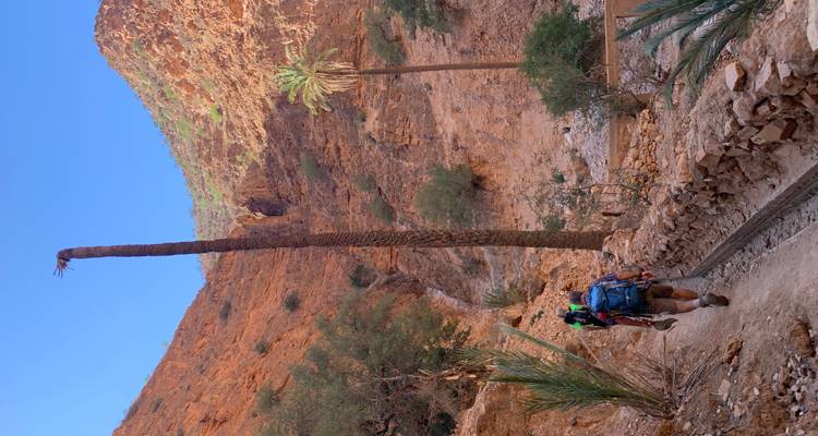Hikers navigating a rugged mountain landscape under clear skies.