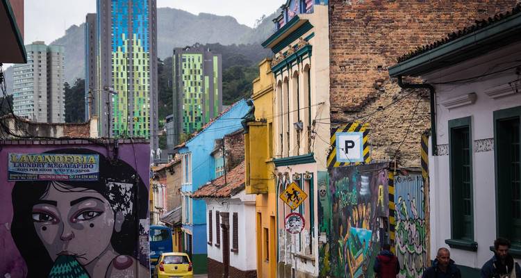 A colorful street with artistic murals and a modern city skyline in the background.