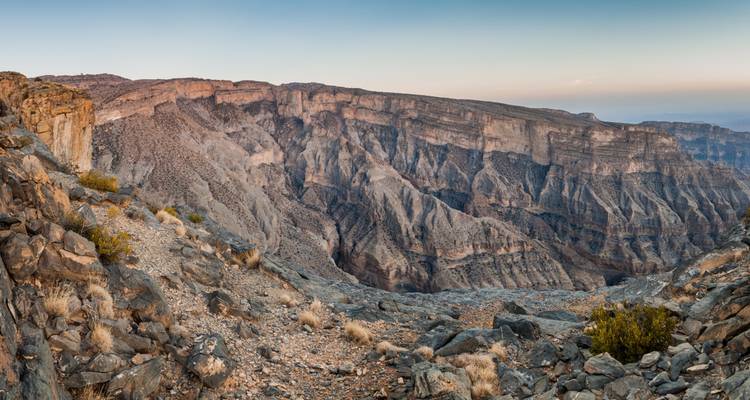 A dramatic and rugged canyon landscape under a clear sky.