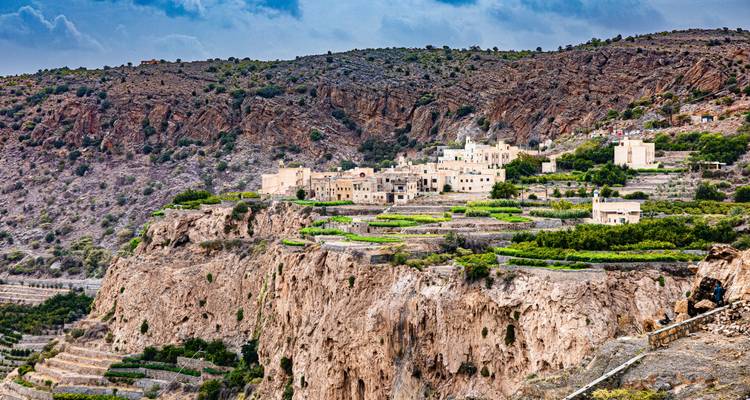 A scenic village perched on a rugged cliff with greenery on a clear day.