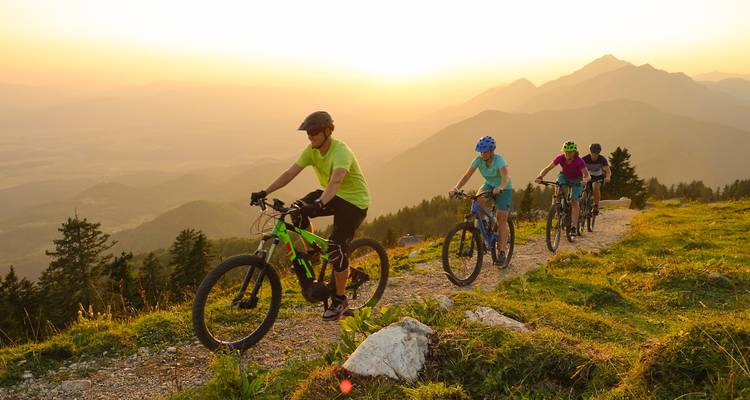 Groupe de cyclistes au coucher du soleil sur un sentier de montagne.