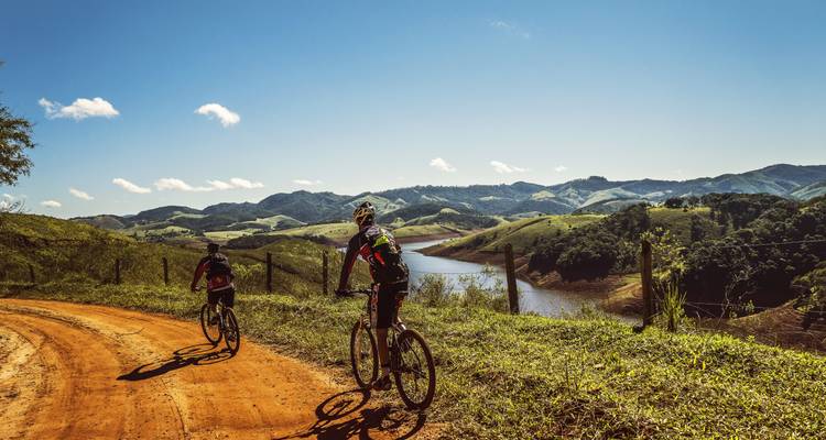 Cyclistes roulant le long d'une rivière avec des montagnes pittoresques.