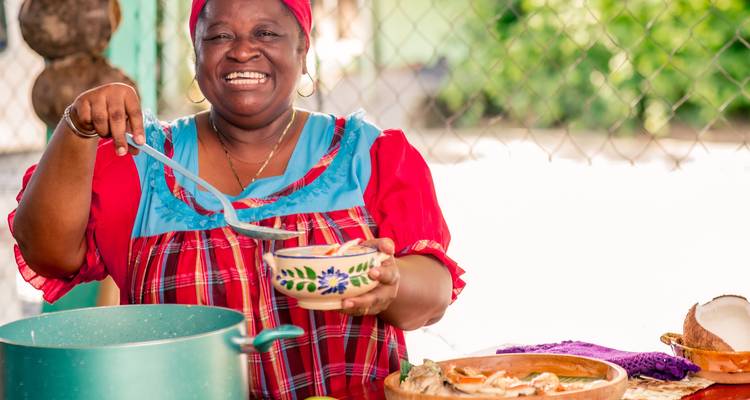 Femme souriante servant de la nourriture avec une louche.