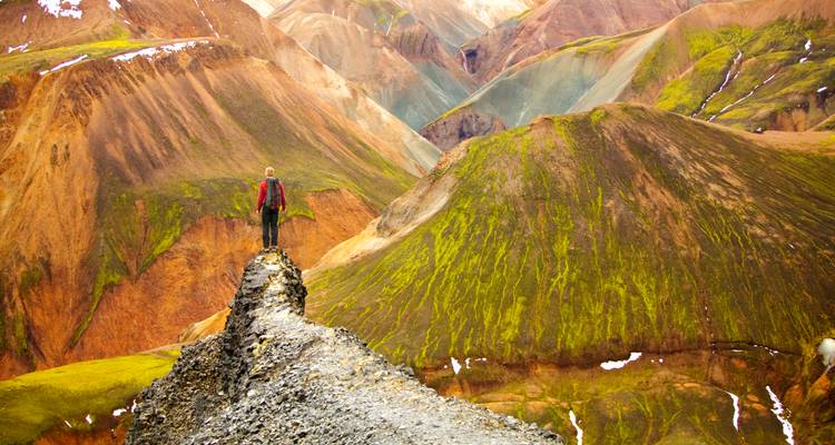 Randonneur debout sur une crête volcanique colorée.