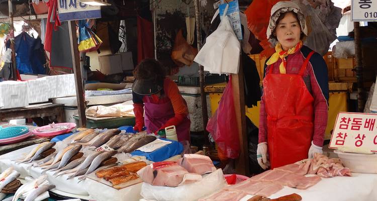 Market stall with fish and a female vendor.