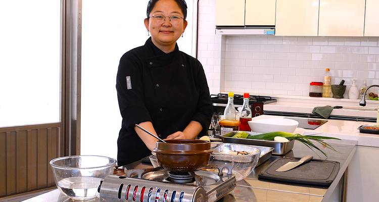 Woman in a kitchen preparing ingredients at a counter.