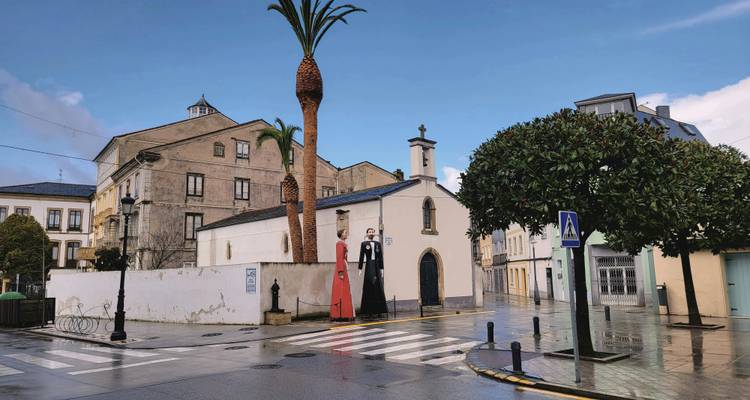 A street scene featuring unique large figures and a small church.
