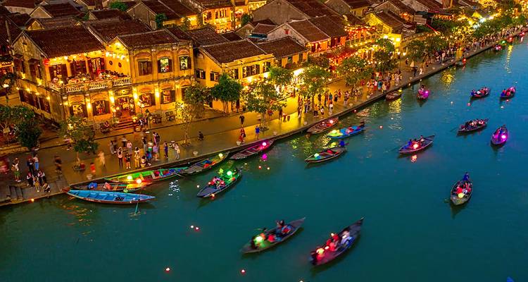 Scène de canal animée avec des bateaux et des bâtiments illuminés.