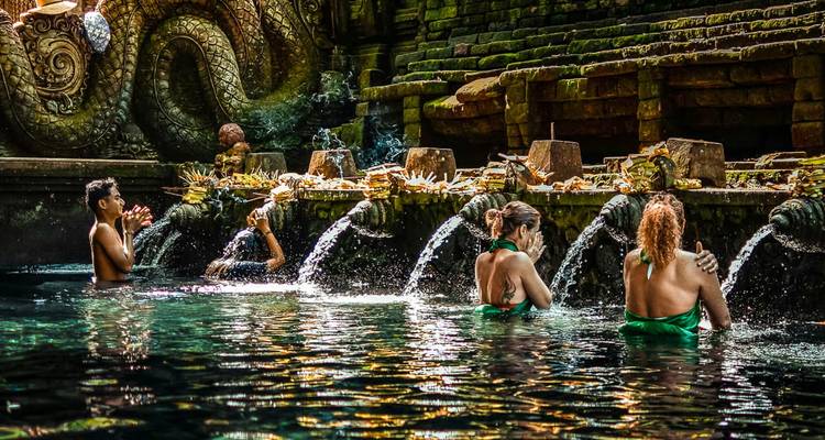 People performing ritual in a water temple with multiple fountains.