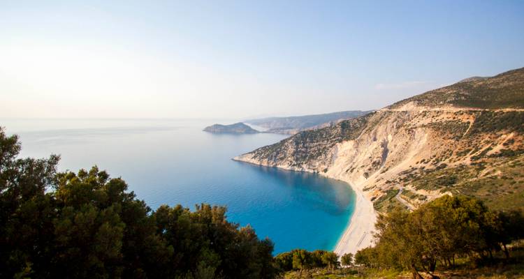 Une vue aérienne époustouflante d'une côte avec une eau bleue claire et une végétation luxuriante.