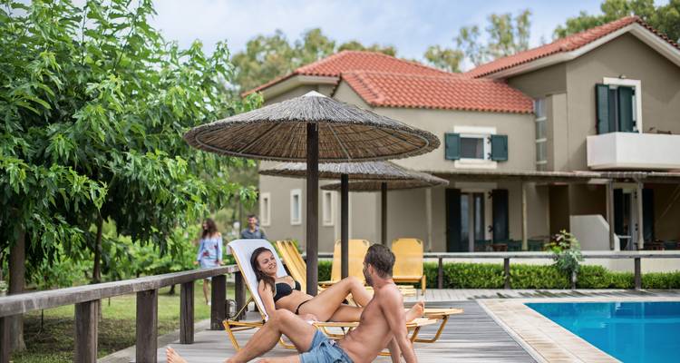 Un couple se détendant au bord d'une piscine avec une maison en arrière-plan.