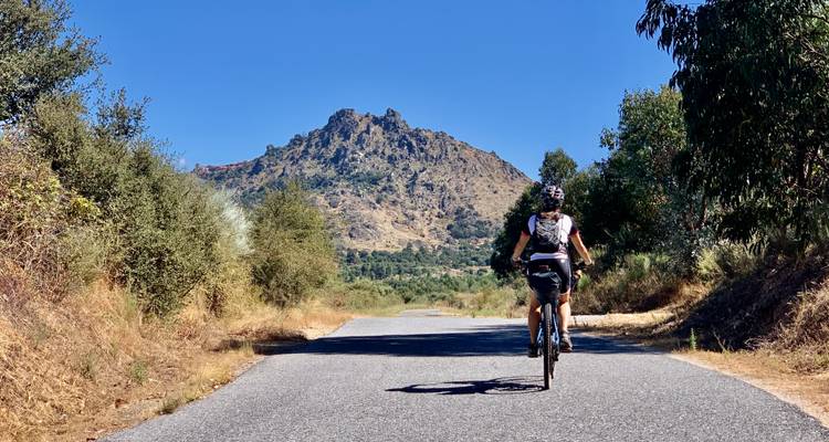 Radfahrer auf einer Straße mit Bergblick.