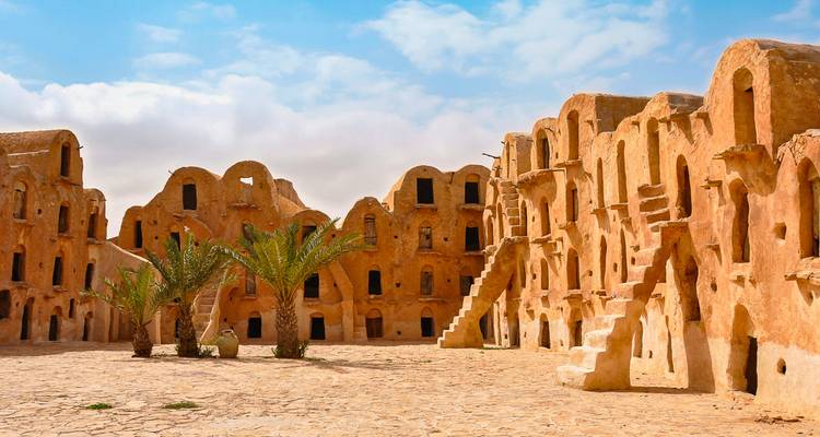 Grenier historique en briques de terre crue avec portes voûtées et escaliers.