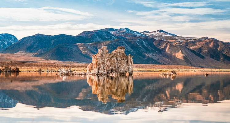 A reflective lake with rocky formations and distant mountains.