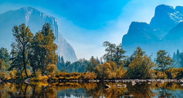 A picturesque view of a national park with forest, river, and mountains.