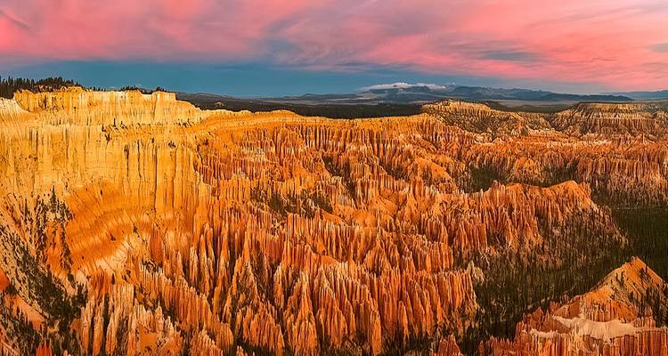 Colorful hoodoos at sunset in a vast canyon.