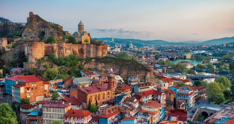 Stadtansicht mit historischer Kirche und alter Festung auf einem steilen Hügel.