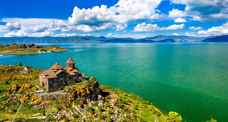Malerische Aussicht auf eine historische Kirche auf einem Hügel mit Blick auf einen großen blauen See.