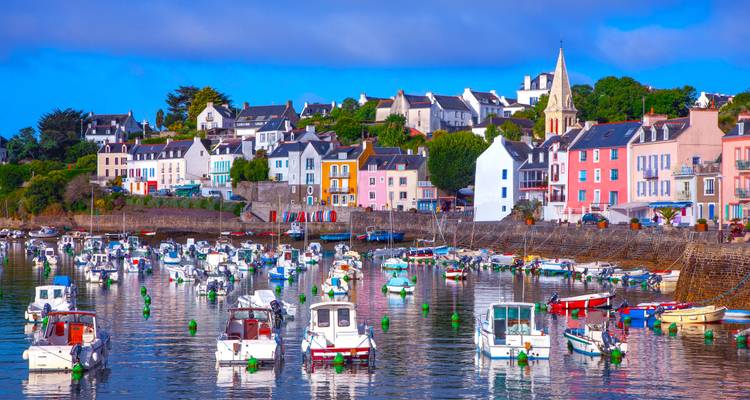 Des bateaux colorés amarrés dans un petit port avec des maisons vives le long du front de mer.